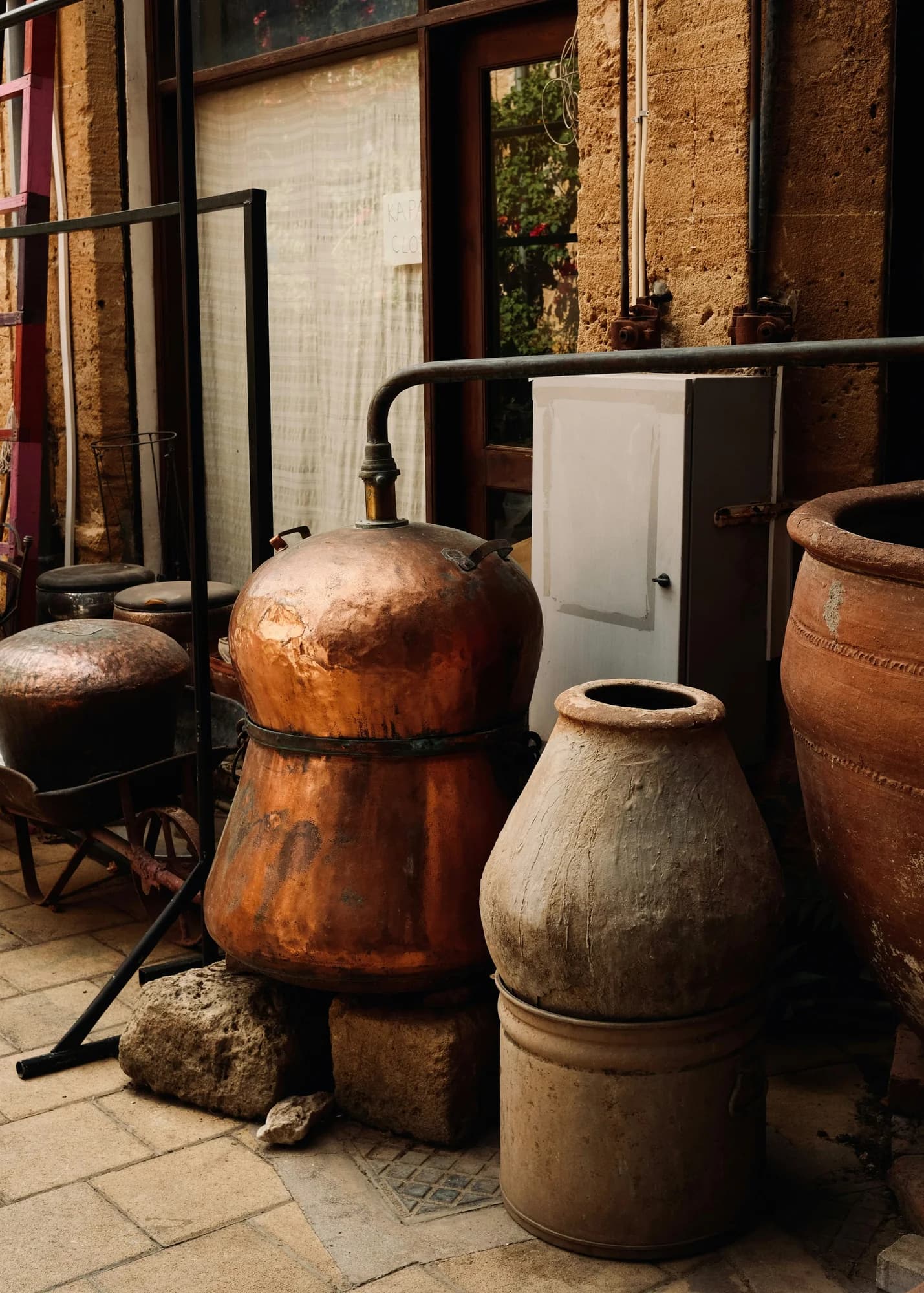 An old copper alembic still beside clay vessels