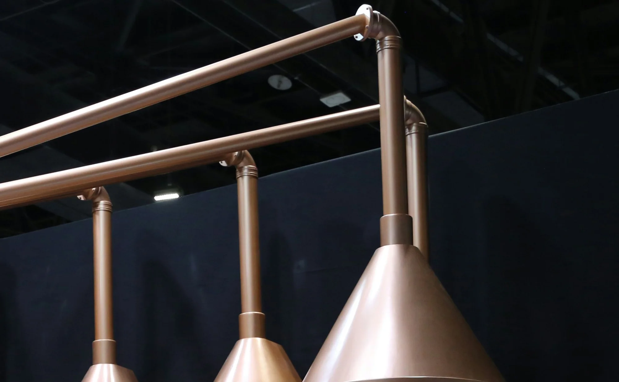 Copper still hoods against a dark ceiling