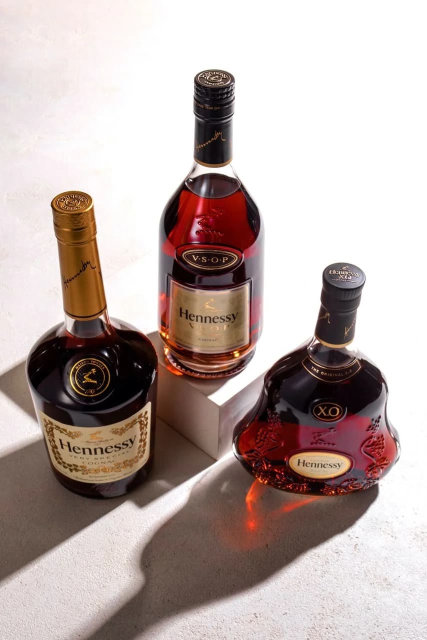 Three bottles of Hennessy in raking light, toned like an old print