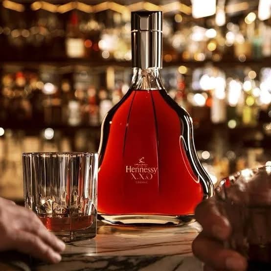 Hennessy X.X.O on a marble bar beside a crystal tumbler, bottles glowing behind